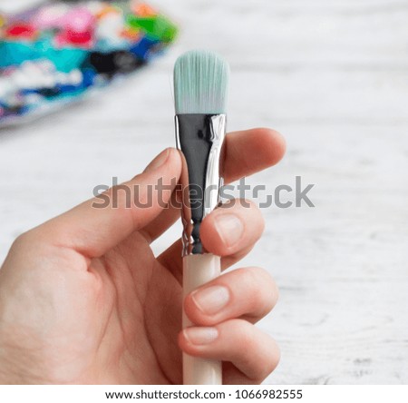 Womans hand with paint brush on a white background