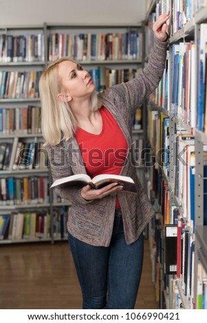 Pretty Female Student With Books Working in a High School Library