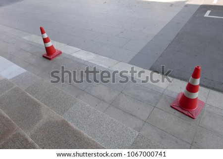 two red traffic cones with two stripe lines each on footpath
