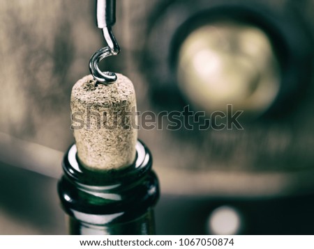 Opening wine bottle. Oak wine keg at the background.