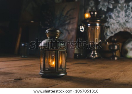 Coziness warmth atmosphere in room on eve of holiday. Beautiful art candlestick illuminates room on wooden floor on gifts background. Candle flame gives festive mood. Expectation of Christmas.