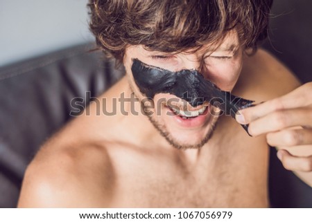 Happy man with black mask on the face. Photo man receiving spa treatments. Beauty Skin care concept