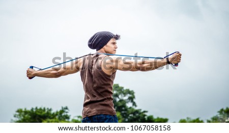 Fit young man exercising with resistance band outdoors Royalty-Free Stock Photo #1067058158