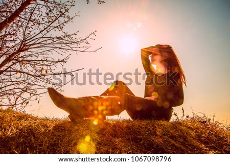Spring background with blooming trees and silhouette of yound woman. springtime season. garden with tree and flowers. cute girl sit on dry spring grass. sun rays. sun light.