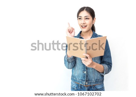 Portrait of attractive asian student ( woman ) standing holding reading a book with copy space over white background with finger point up. Education test exam thinking concept 
