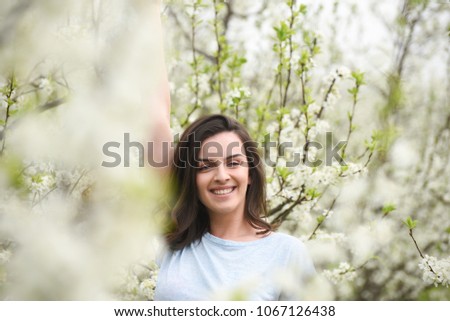 Portrait of happy girl in blooming orchard. Beautiful woman enjoy in nature in spring