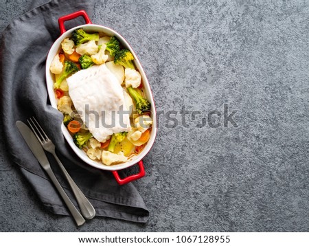 Fish cod baked in the oven with vegetables - healthy diet healthy food. Gray stone background, copy space, top view.