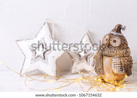 Decorative cuty owl and two Christmas toys star on white textured  background. Place for text. Christmas  decorations.