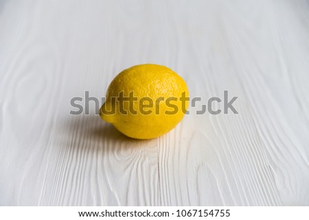 Single whole lemon on white wooden surface close