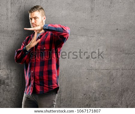 Young handsome man serious making a time out gesture with hands
