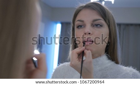 Beautiful Woman Putting Lipstick on Lips in Mirror