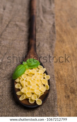 Dry Italian pasta in a spoon on old wooden background. Selective focus.