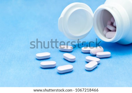 Pills spilling out from a bottle Royalty-Free Stock Photo #1067218466