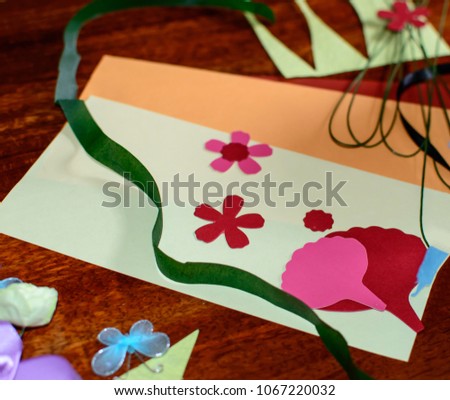 Arts and crafts with paper cut outs ribbon and flowers and butterfly objects on wood table