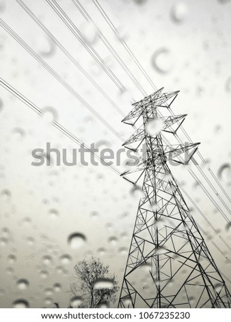 Raindrops on glass with high voltage electrical pole