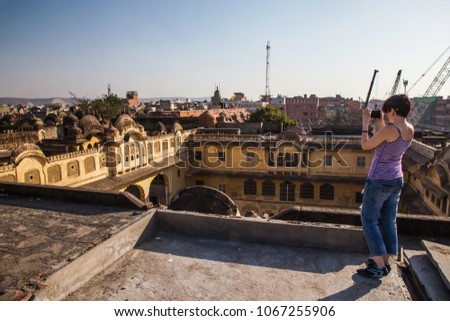 A girl takes pictures of the old part of the city on a smartphone. Old Eastern Buildings Jaipur. India