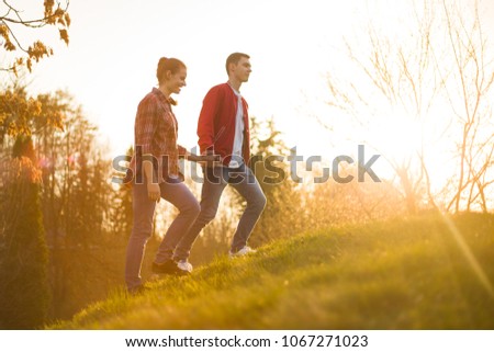 I love you!Girl and boy holding hands because they are in love. Boy is leading girl on hill. They are in beautiful warm summer light background during sunset. Love is in the air.Romance is everywhere.