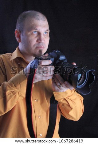 Professional photographer in the Studio on a black background with a camera in hand.