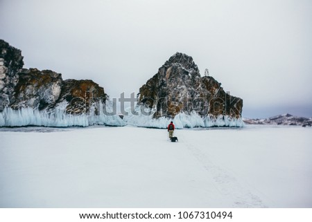 A group of tourists walks with sledges and backpacks in winter in the cold on the ice of Lake Baikal.
