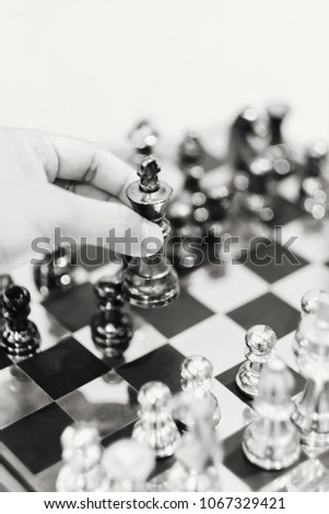 The competition of chess game between black and white teams. selective focus at left hand holding the king of black team. concept of competition and leadership Composing picture with monochrome.