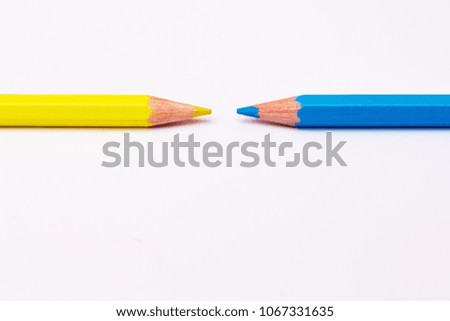 two pencils of yellow and blue, symbolize the opposite