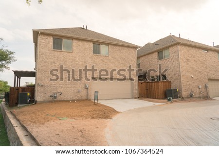 Typical rear entry garage of brand newly built house sold signs in Texas, USA. Row of detached lot garage in back, parking area behind new-established development, unfinished landscape neighborhood