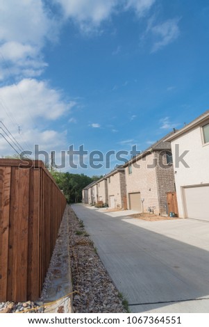 Typical rear entry garage of brand newly built house sold signs in Texas, USA. Row of detached lot garage in back, parking area behind new-established, unfinished landscape neighborhood. Blue sky
