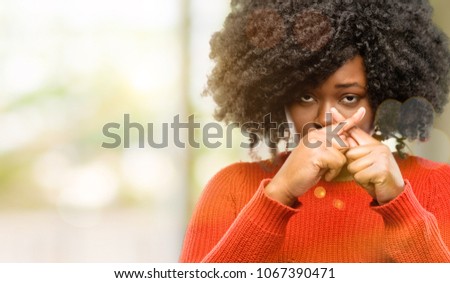 Beautiful african woman annoyed with bad attitude making stop sign with hand, saying no, expressing security, defense or restriction, maybe pushing, outdoor