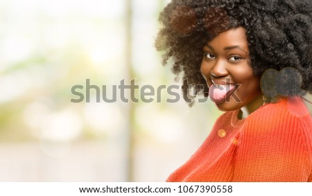 Beautiful african woman sticking out tongue at camera at sign of disobedience, protest and disrespect, outdoor