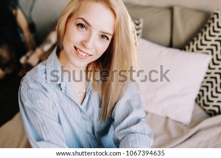 Portrait of a young beautiful woman in bed in the morning at home. Blonde girl in scandinavian interior. Atmospheric hygge style. Good morning. Lifestyle.