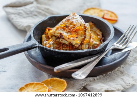 Traditional French crepe Suzette with orange sauce in a cast iron pan. Royalty-Free Stock Photo #1067412899