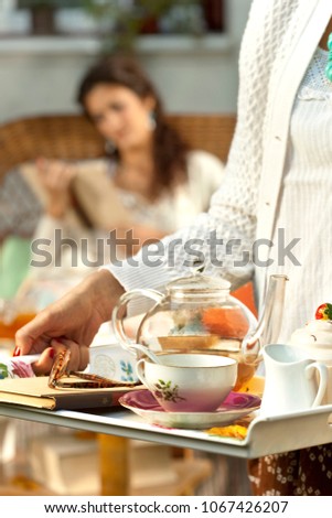 Close up on a tea server with woman reading in the background