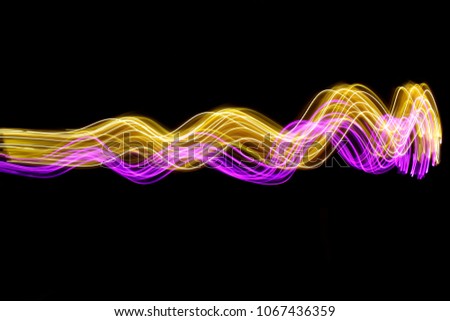 Pink and gold light painting photography, long exposure photo of fairy lights in a rippling, curvy wavy pattern, against a black background