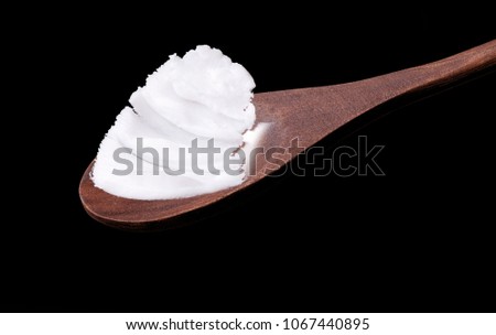 Rustic wooden spoon with pork fat, on the black background.