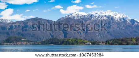 Overview of Lake Como with Bellagio. In the background snowy mountains and blue sky with small white clouds.