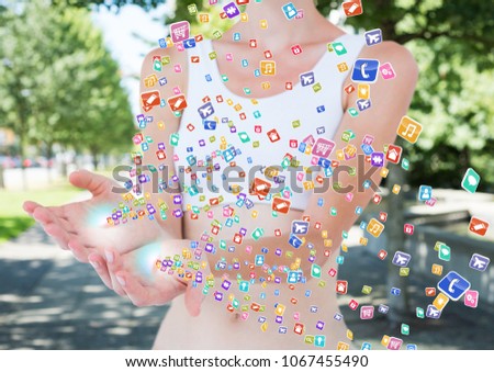 hands with application icons coming up form it. Blurred park background