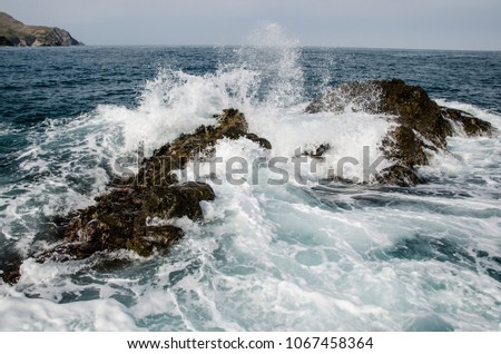 Rolling wave slamming on the rocks of the coastline