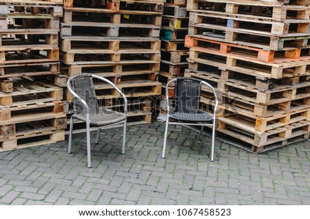 two wicker chairs placed in front of stacks of pallets