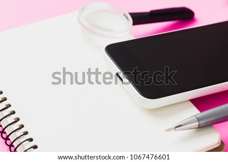 Smartphone, magnifying glass, pen and notepad. concept of search.