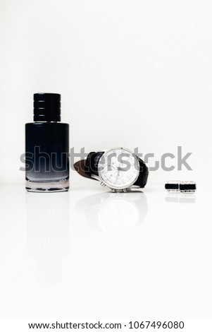 close up of perfume, stylish black watch and cufflinks on a white background