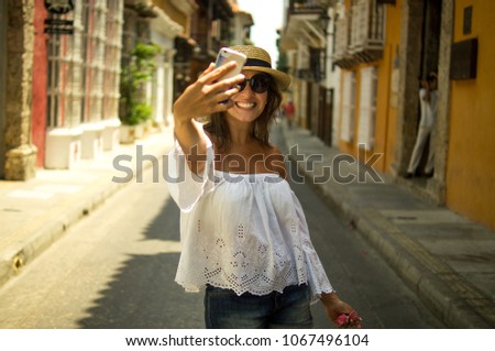 Beautiful young woman taking a self portrait on an old street