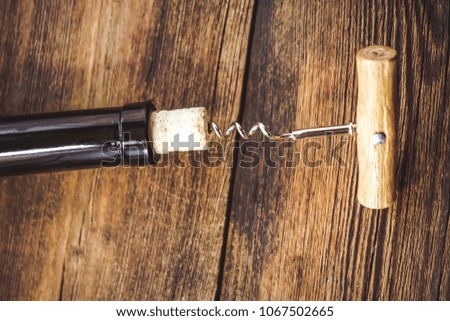 a bottle of wine. corkscrew for cork. wooden background.
