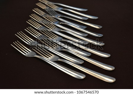 Arrangement of gray aluminum spoons and fork on a table with dark brown table cloth as background