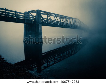 Blue selenium filter of truss footbridge fading into the fog as it spans the lake at Tims Ford State Park in Winchester Tennessee