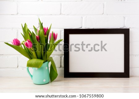 Black brown  landscape frame mockup with bright magenta pink tulip bouquet in the mint green pitcher jar vase. Empty frame mock up for presentation design. Template framing for modern art.