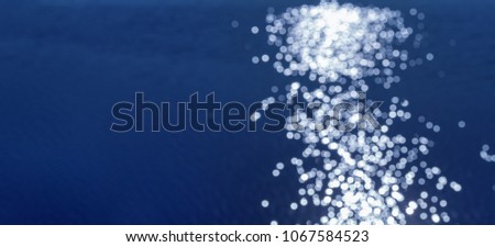 Amazing natural background water surface with path of sunlight reflection. Bokeh pattern on blue water. Banner with copy space.