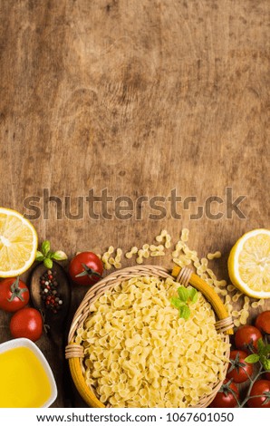 Dry Italian pasta in basket on old wooden background. Selective focus.