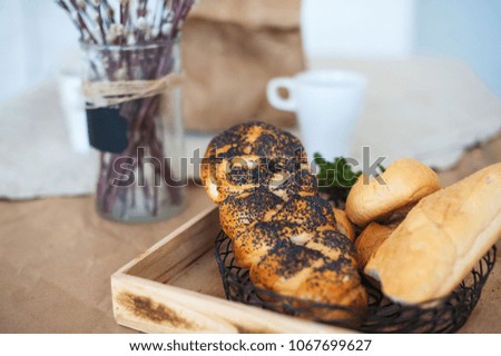 Beautiful picture of food, rolls with poppy seeds in light texture colors. Bread lies in a basket on the background of a rustic table