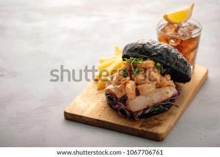Black burger with fish and shrimps. Fishburger with prawns.