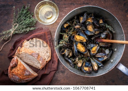 Traditional barbecue Italian blue mussel with farmhouse bread and white wine as top view in a casserole 